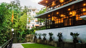 Un edificio moderno con balcón, plantas en macetas y un jardín bien cuidado.