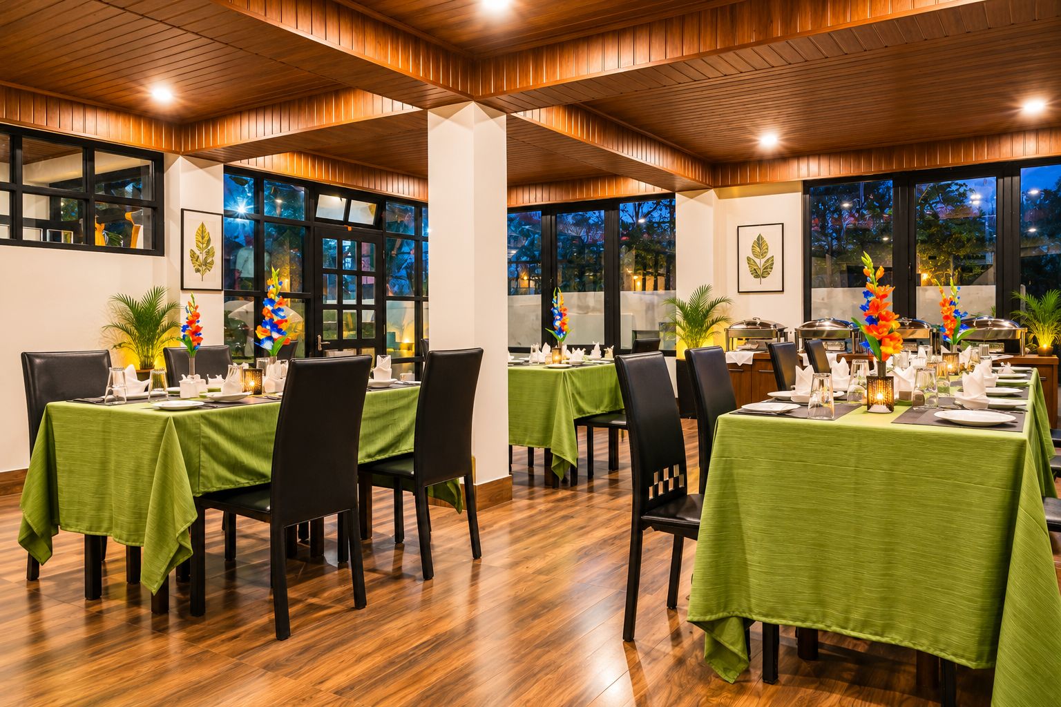A restaurant with multiple tables set for dining, featuring green tablecloths and black chairs.