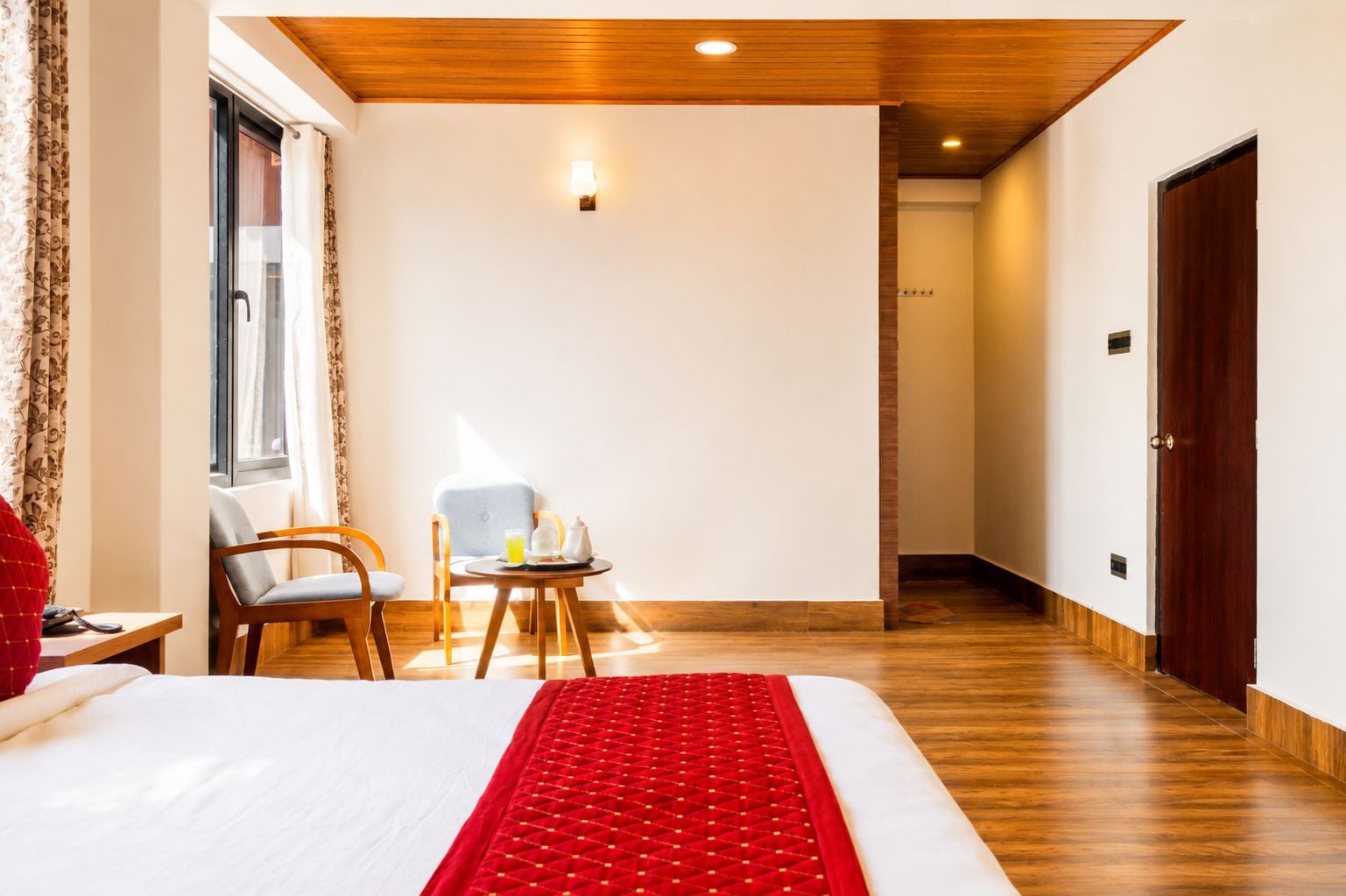 Une chambre d’hôtel avec un lit, un coin salon avec une table et un plancher en bois.