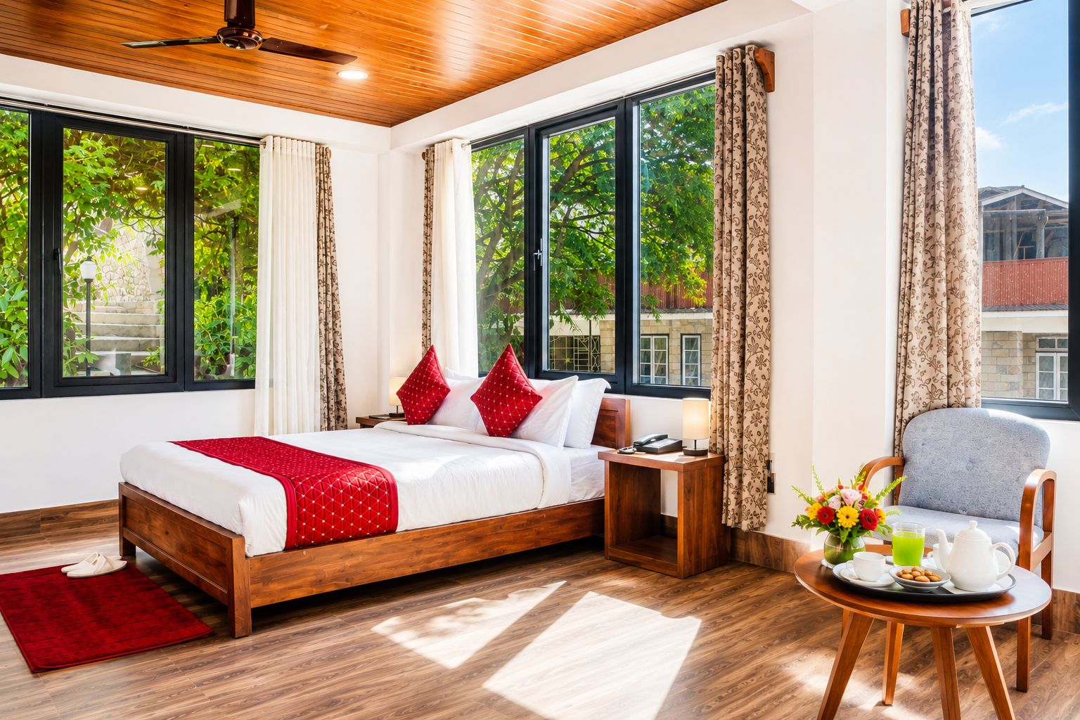 A hotel room with a bed, bedside table, chair, and a small table with a tray of breakfast items.