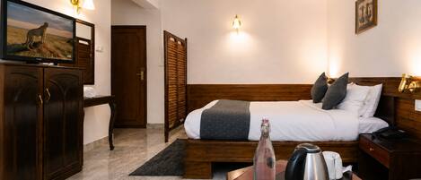 Une chambre d’hôtel avec un lit, un bureau doté d’une bouilloire, une bouteille et un tableau accroché au mur.