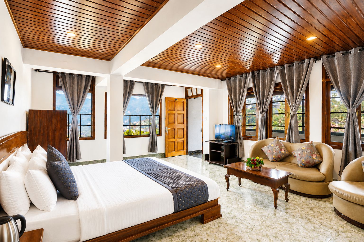 A hotel room with a large bed, a sofa, a television, and a view of the outdoors.