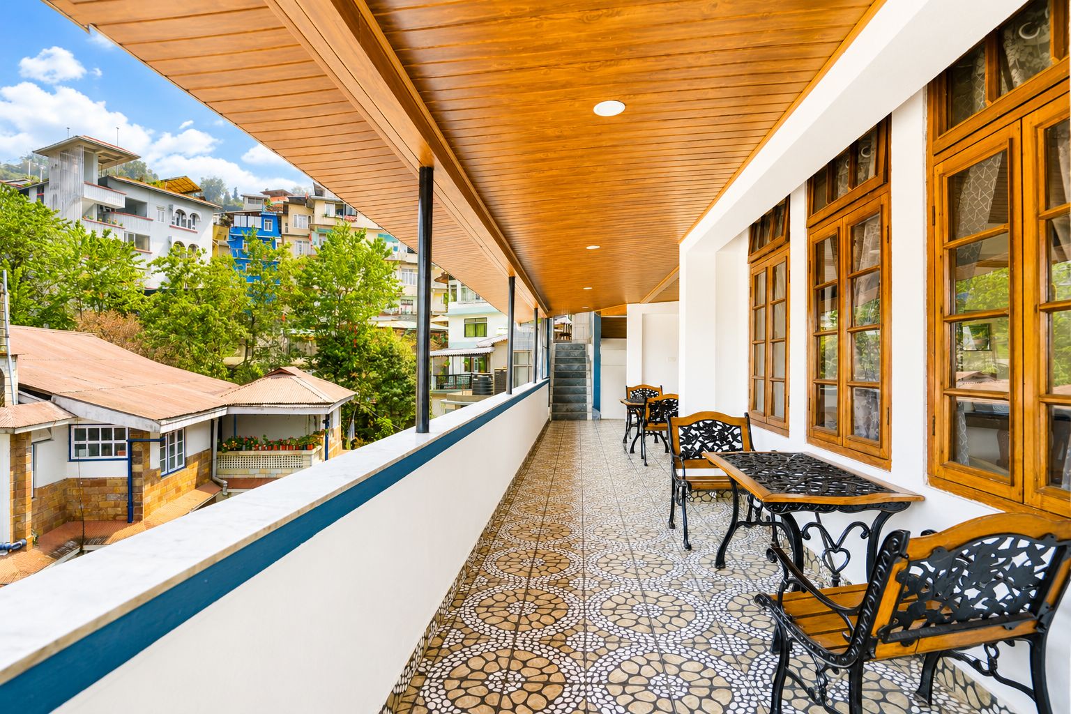 Un balcon fermé doté d’un sol carrelé, de meubles en bois et de grandes fenêtres.