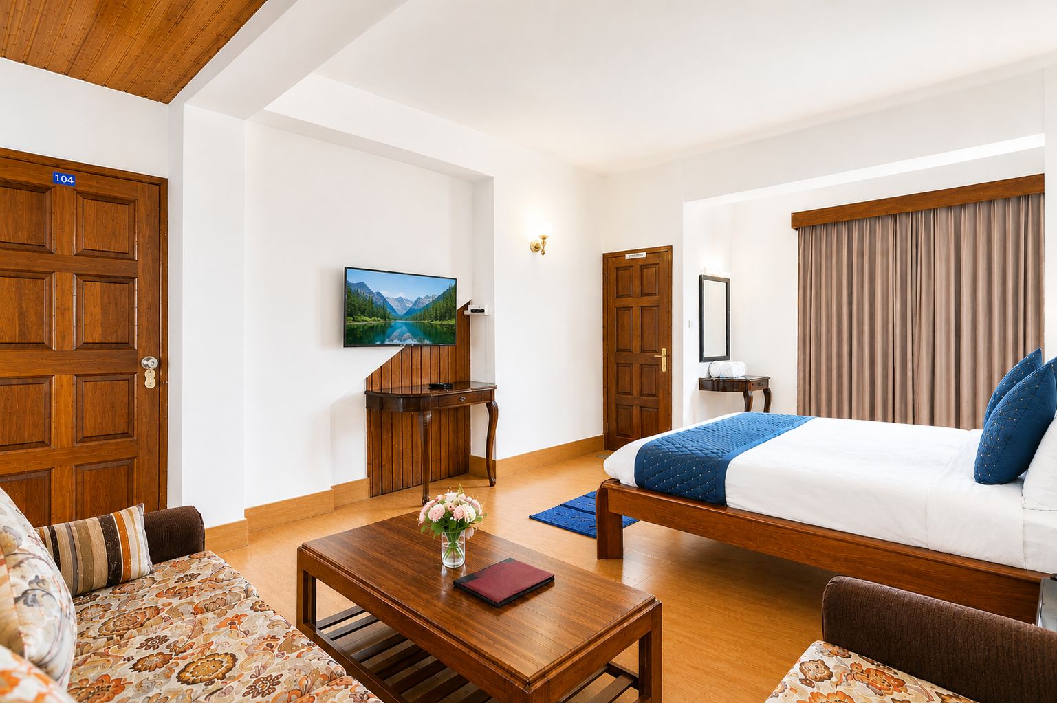 Habitación de hotel con cama, escritorio de madera, sofá, televisor y un cuadro en la pared.