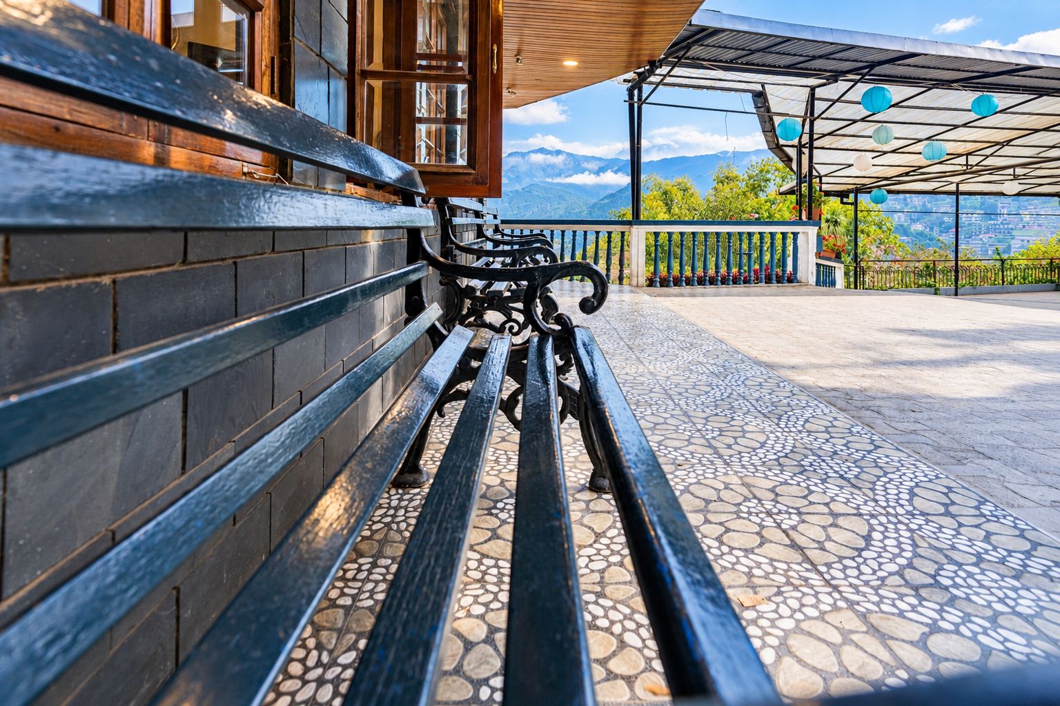 Un banc avec un sol carrelé, un mur en bois et une vue sur les montagnes en arrière-plan.