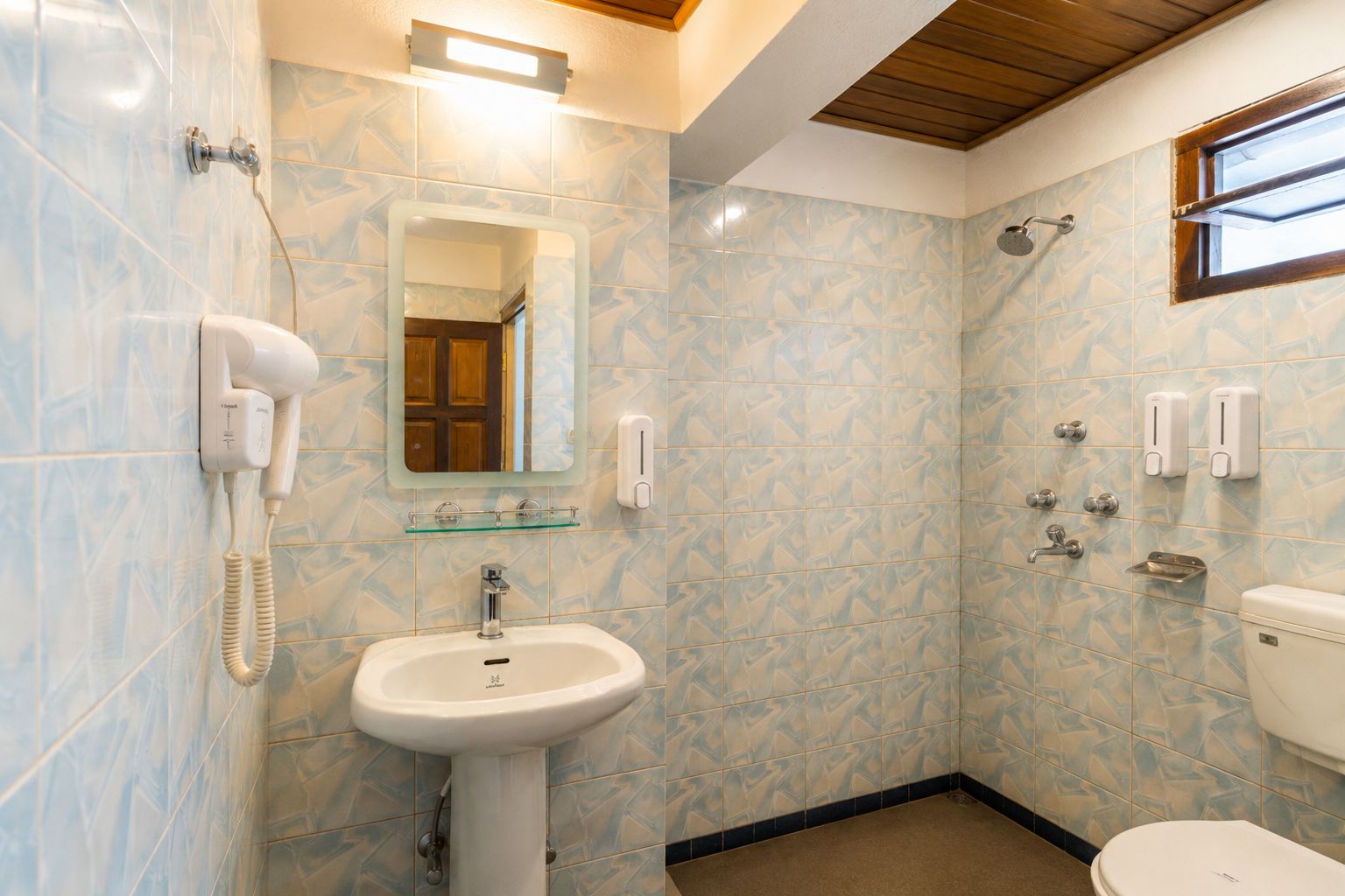 A bathroom with a sink, mirror, shower, and toilet.