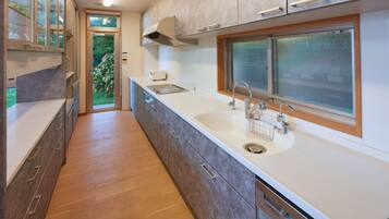 A modern kitchen with a large window, wooden flooring, and built-in appliances.