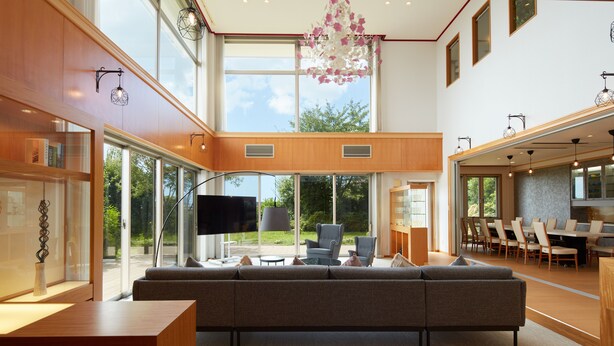 Una sala moderna con un amplio sofá modular, un televisor de pantalla plana y un comedor con una mesa grande y sillas.