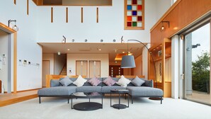 Un interior moderno con un sofá modular, mesas redondas de centro y un ventanal con vistas al exterior.