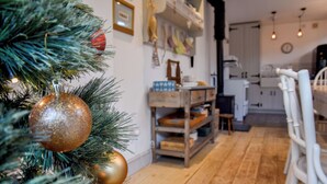 Una cucina accogliente con pavimento in legno, un'area pranzo con sedie bianche e un albero di Natale decorato.