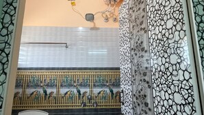 A bathroom with a shower, a wall-mounted air purifier, and a decorative panel with a bird mural.