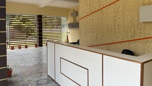 A reception area with a patterned floor, a reception desk, and a wall-mounted electrical panel.