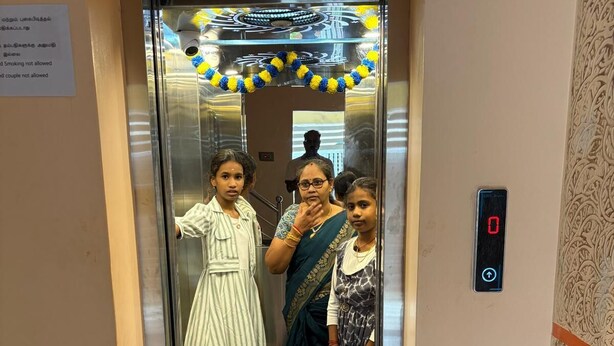 An elevator with a welcome mat, a digital display, and a patterned wall.