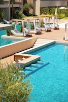Zona de piscina con múltiples tumbonas y una terraza de madera.