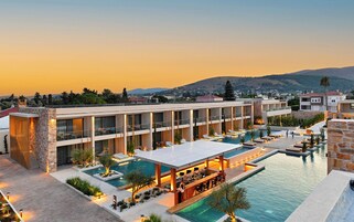 Un hotel moderno con piscina en la azotea, bar al aire libre y varios balcones.