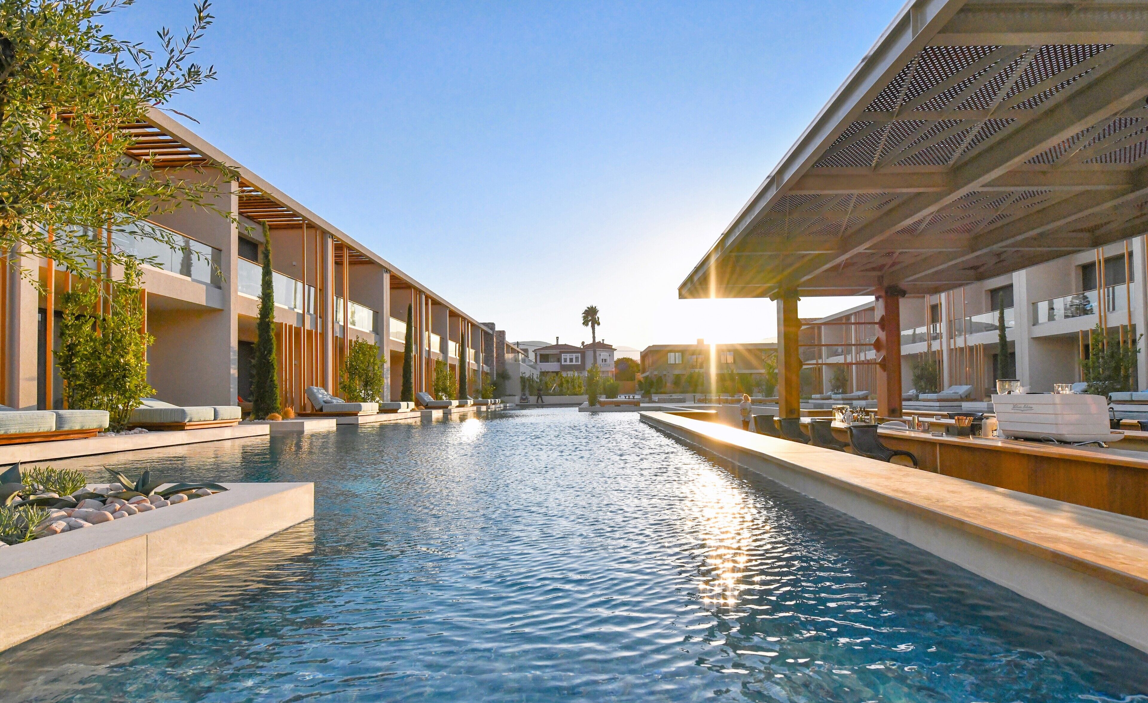 Un hotel moderno con piscina central, zonas de descanso y vistas despejadas del paisaje circundante.