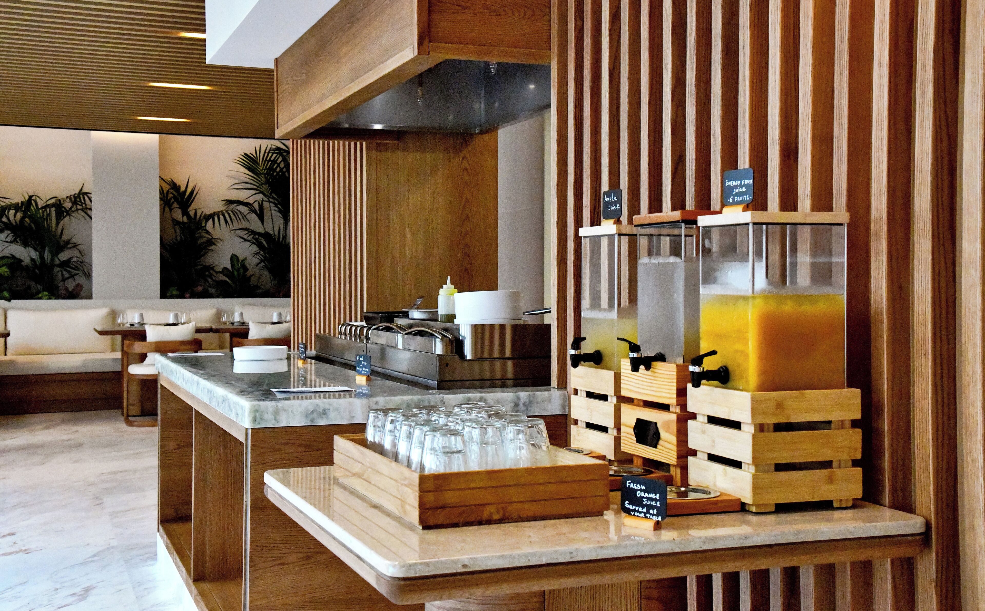 Un banco colazione con angolo succhi di frutta, casse di legno e un’area salotto con divano e tavolo.