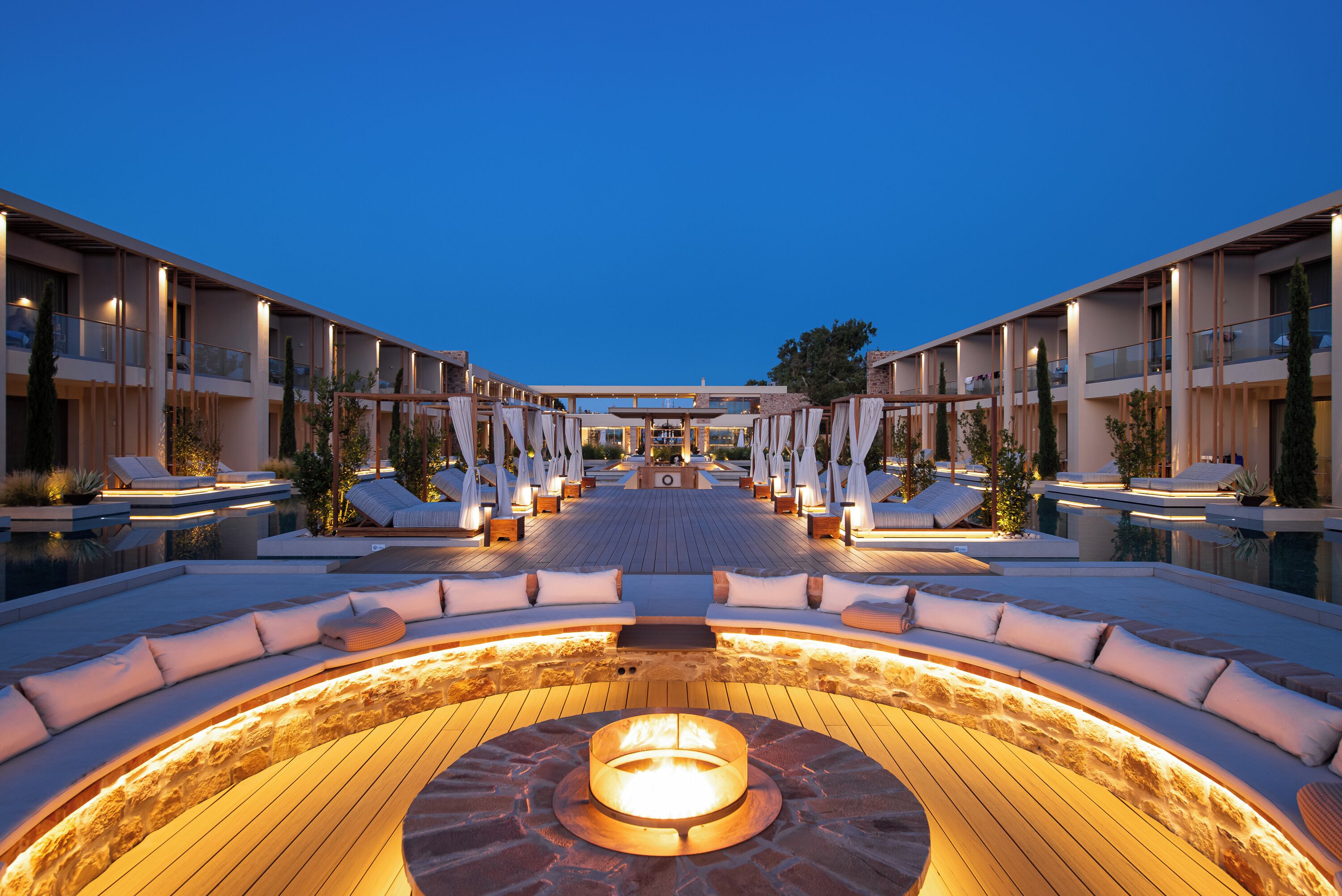 Hotel con patio central que cuenta con una chimenea, asientos de salón y un área de piscina.