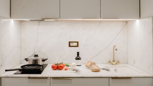 A kitchen with a marble countertop, a stove, a sink, and a cabinet.