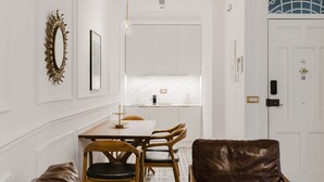A dining area with a white table, wooden chairs, a brown leather chair, and a patterned floor.