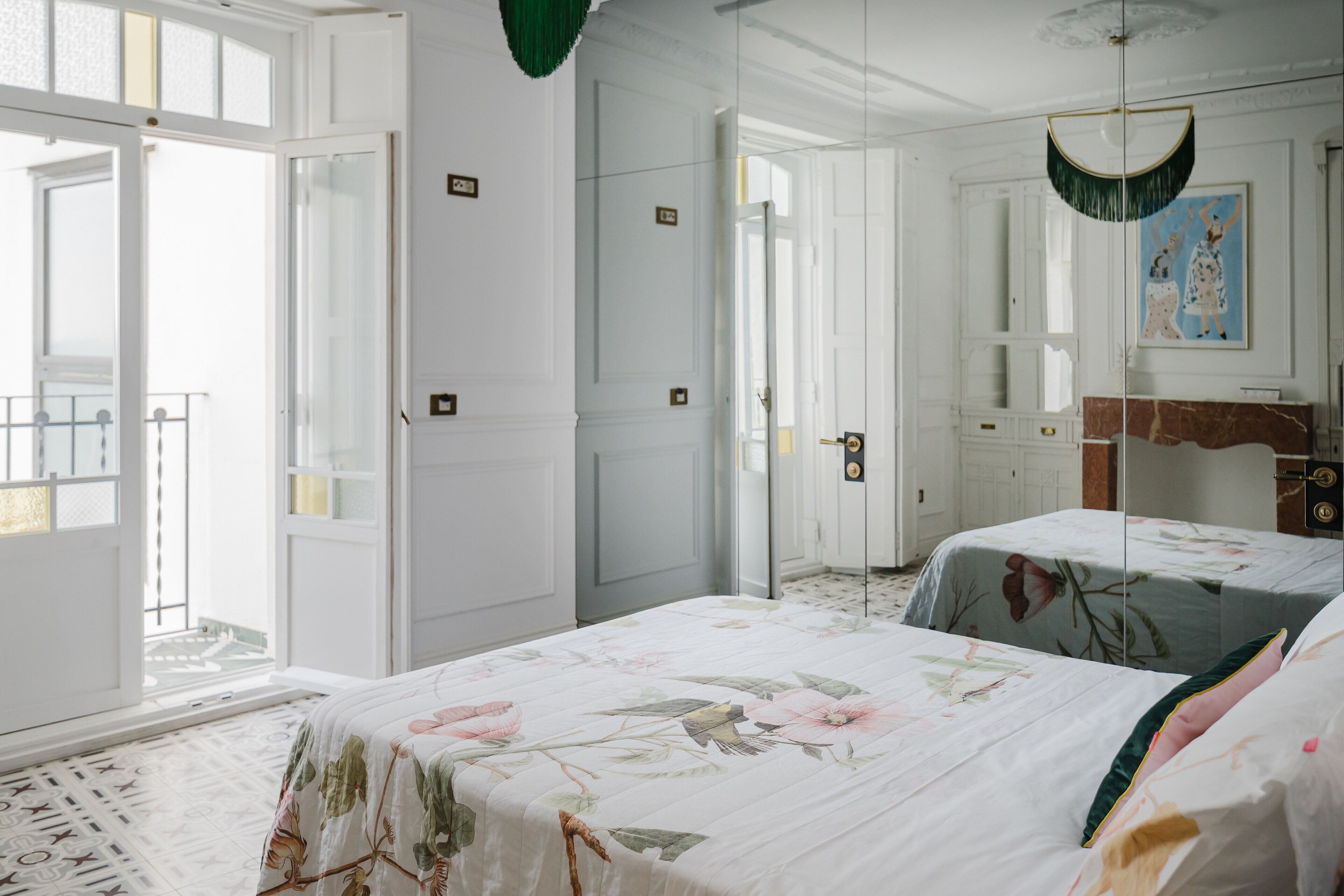 A bedroom with two beds, a large window, and a door leading to a balcony.