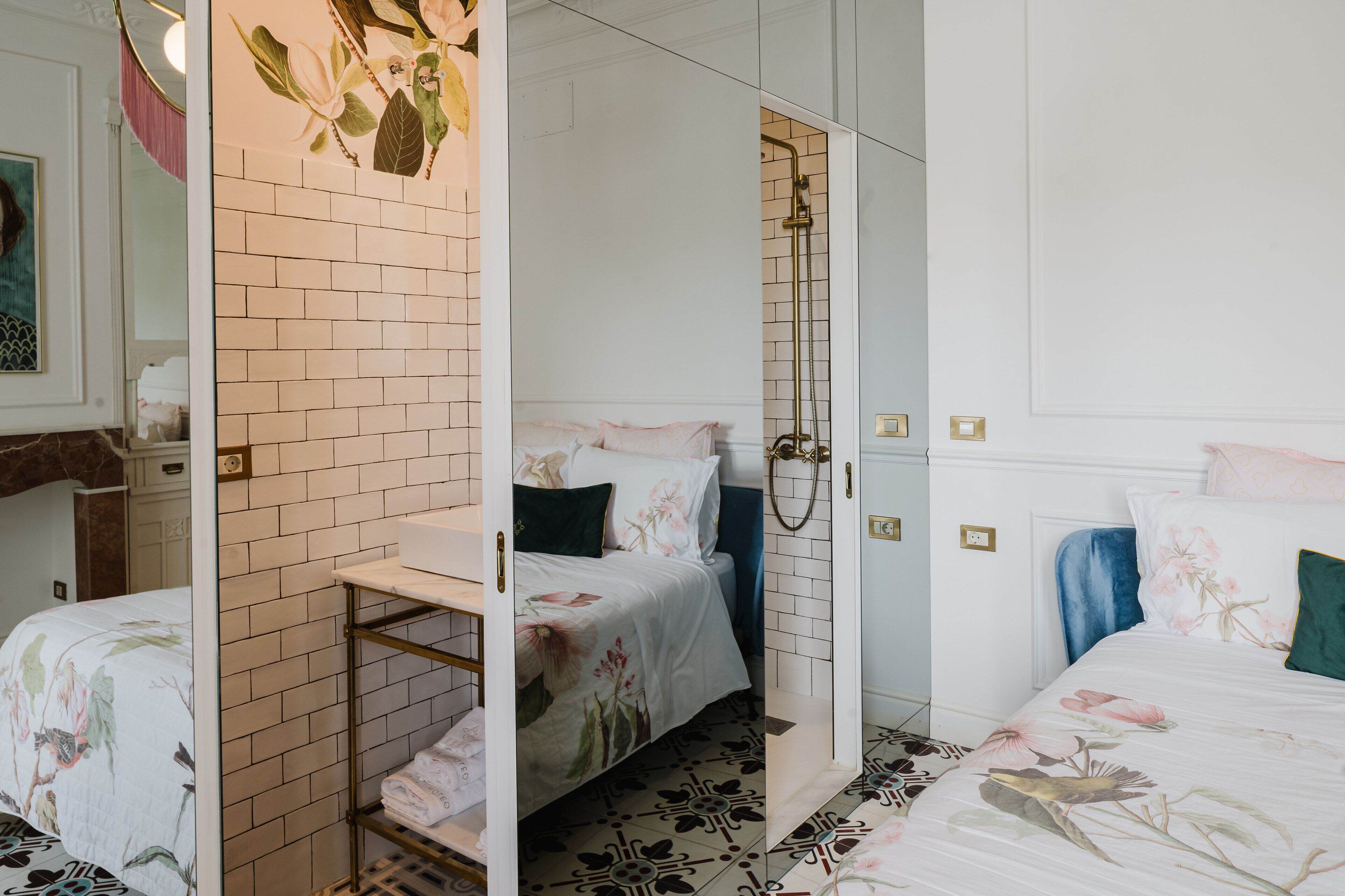 Une chambre à coucher comprenant un lit, une table de chevet, un miroir et un espace douche.