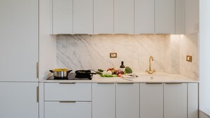 Eine moderne Küche mit weißen Schränken, einer Marmor-Spritzschutzwand und einem Edelstahl-Spülbecken.