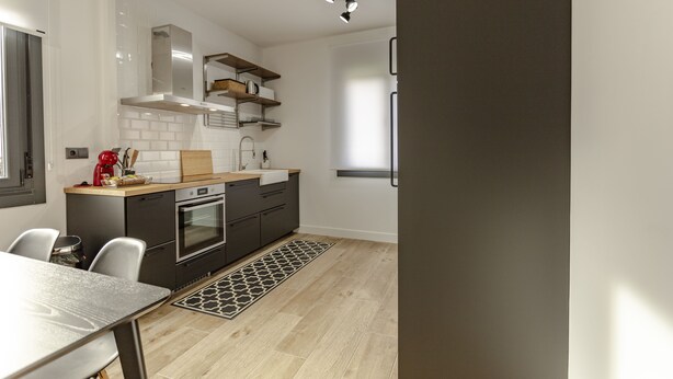 Una cocina moderna con comedor, que incluye un horno empotrado, un lavamanos y una encimera con estantes de almacenamiento.