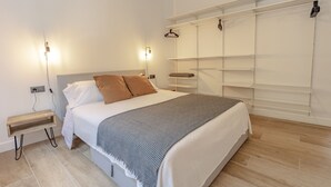 Un dormitorio moderno con cama, mesitas de noche, armario e iluminación empotrada.