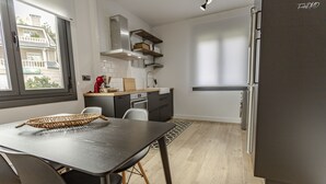 Una cocina moderna con comedor, que presenta un amplio ventanal, electrodomésticos integrados y un diseño minimalista.