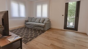 Una sala de estar moderna con un sofá gris, un tapete estampado y un televisor sobre una mesa de madera.