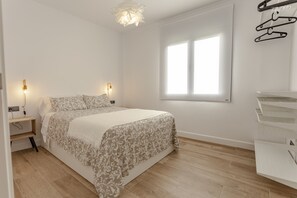 Une chambre à coucher avec un lit, des lampes de chevet, une fenêtre et une commode blanche.