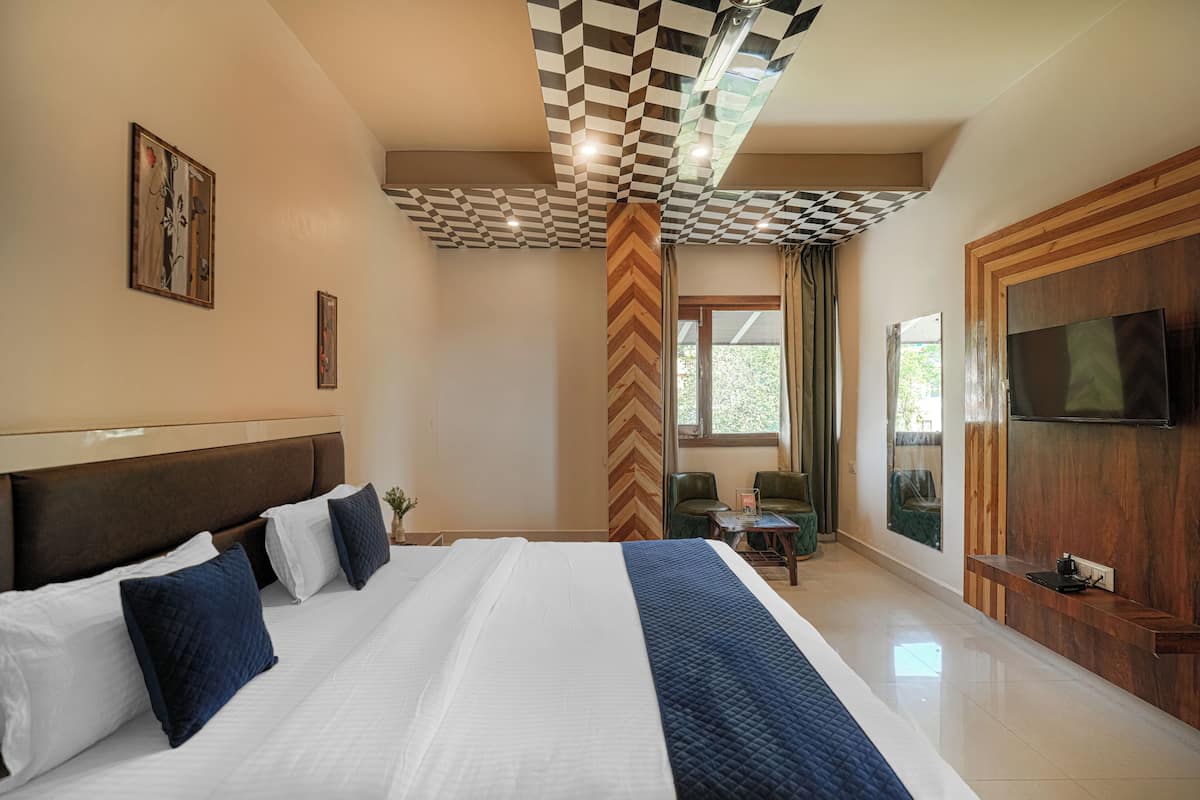 Habitación de hotel con una cama grande, un televisor, un panel de pared de madera y vistas a la vegetación.