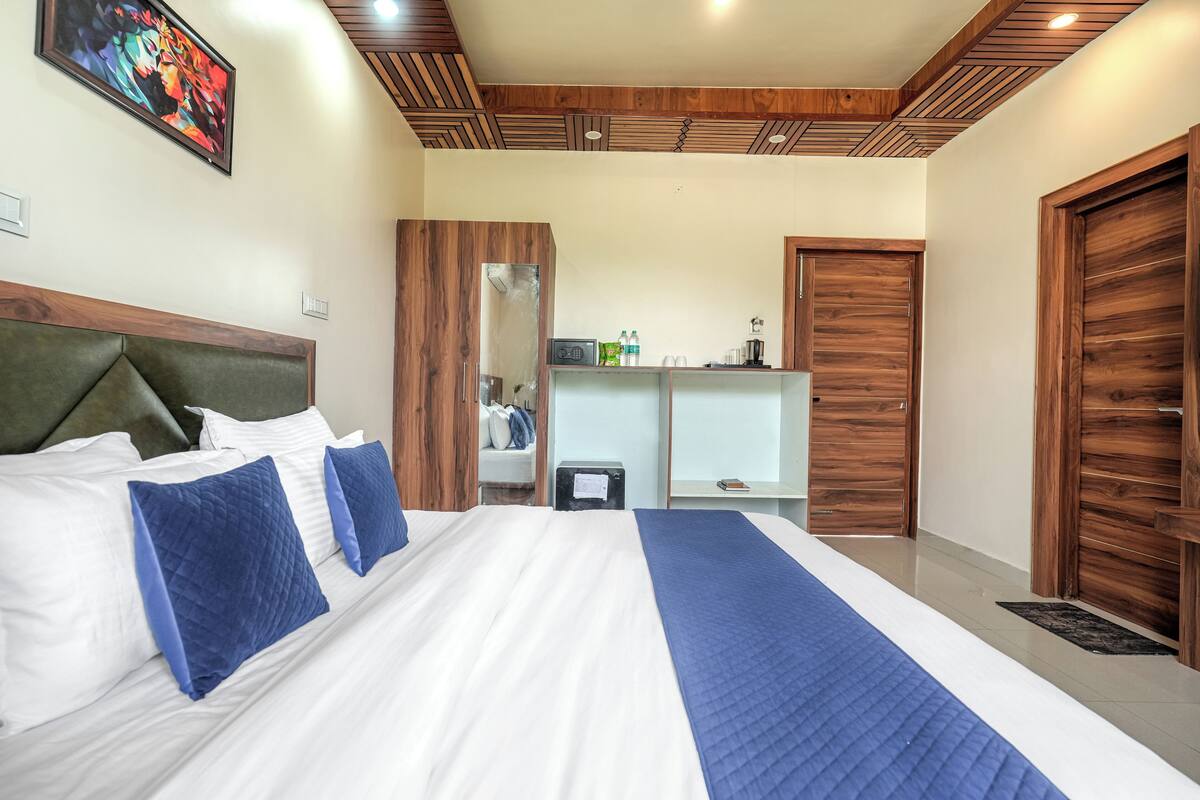 Una habitación de hotel con una cama grande, cabecera de madera y un armario.