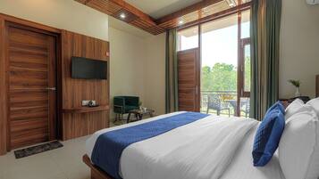 Habitación de hotel moderna con una cama grande, paneles de madera, un televisor de pantalla plana, un balcón con vistas y una pequeña mesa con una silla.