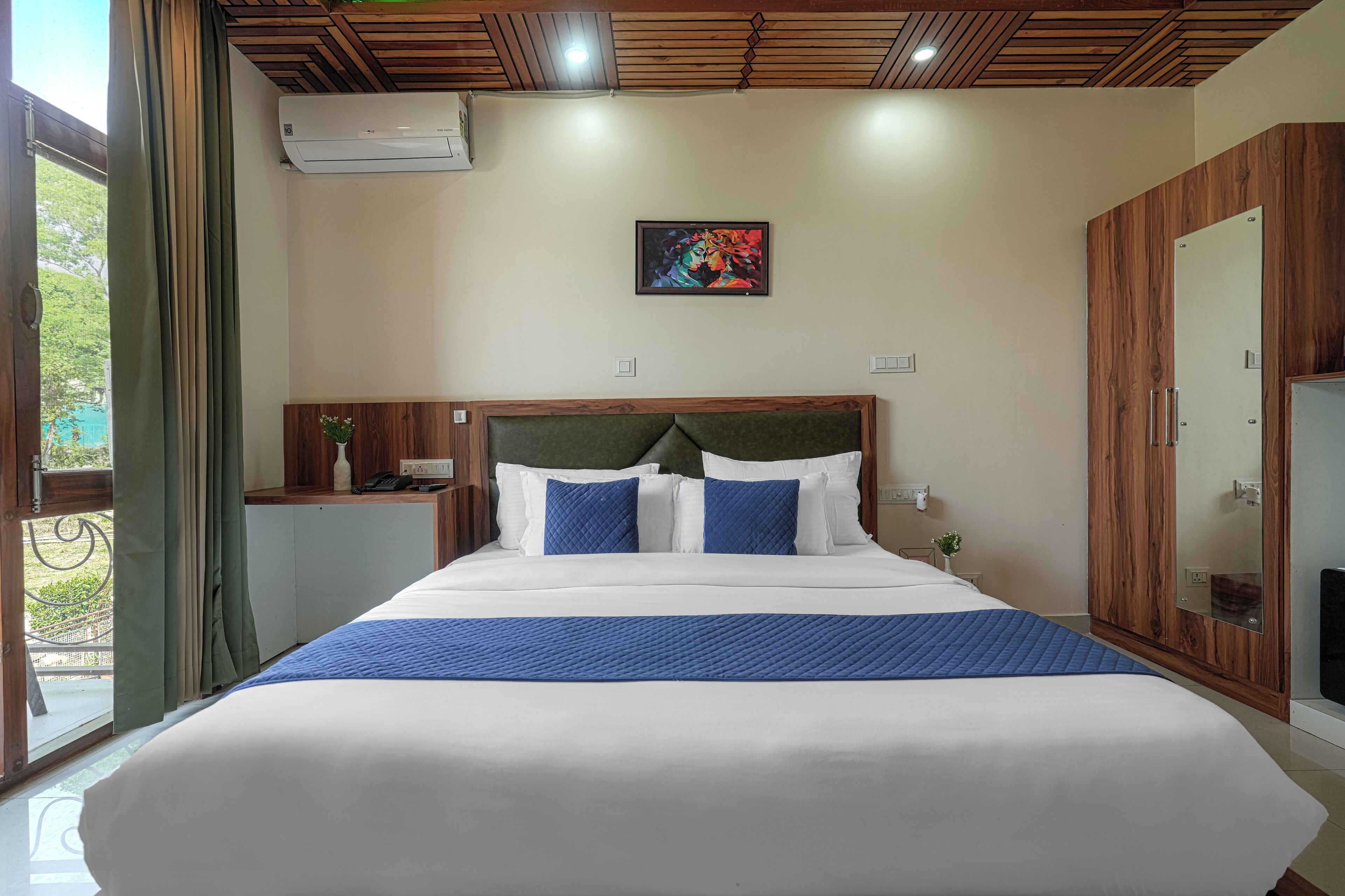 A neatly made bed with a blue accent, a wooden headboard, and a painting on the wall.