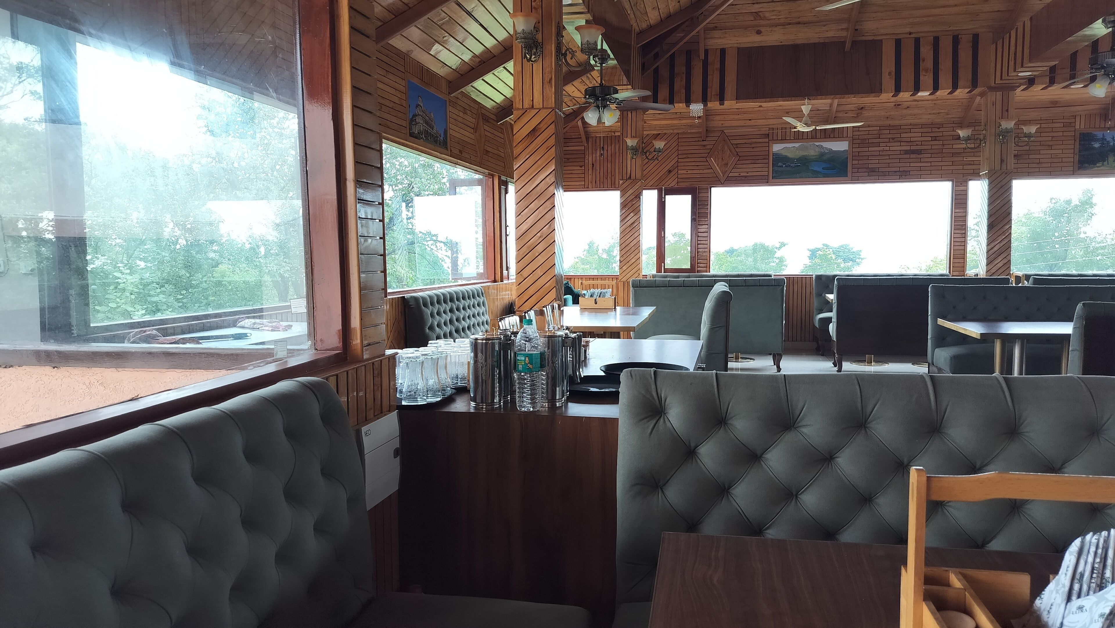 Un restaurante con interior de madera, asientos acolchados y grandes ventanales que ofrecen vistas al exterior.
