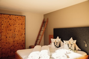 Ein Schlafzimmer mit einem Holzkasten, einem Bett mit weißer Bettwäsche und zwei Kissen mit Kuhmotiven.