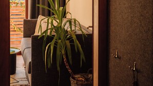 Ein Innenraum mit einer Couch, einer Lampe, einer Pflanze und einer Tür mit Kleiderhaken.
