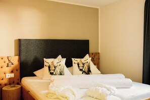 Habitación de hotel con una cama grande, dos almohadas con diseño de vaca, una mesita de noche de madera y un cabecero de madera.