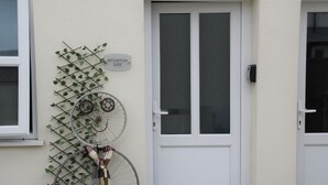 A white door with a sign reading "BROMPTON SUITE" and a bicycle rack with two bicycles. - The Old Bike Shop Accommodation (Norwich)