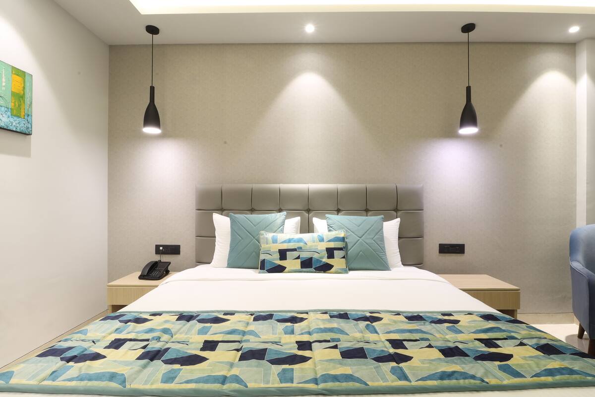 Una habitación de hotel con una cama, dos mesitas de noche, un teléfono y una silla azul.