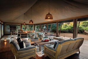 A spacious tented area with wooden furniture, hanging lamps, and a view of the surrounding greenery. - Hutwini Walking Camp by RETURN Africa (Mutale)