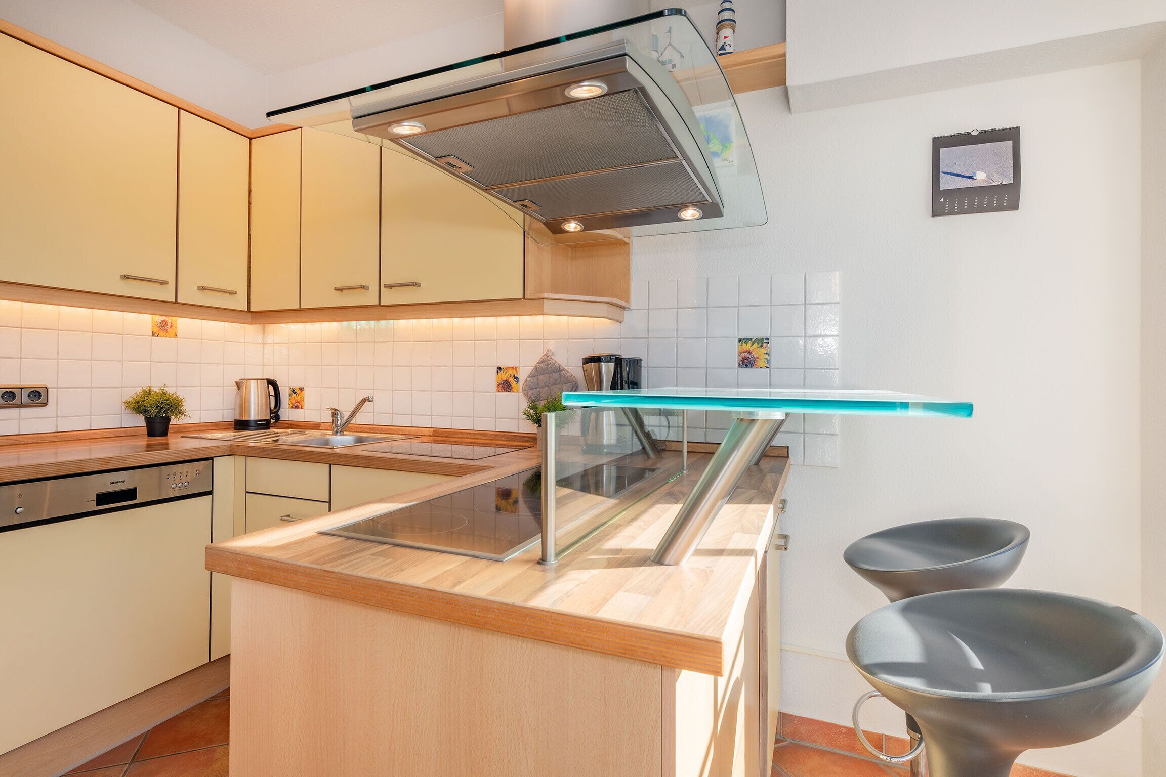 A modern kitchen with a built-in dishwasher, a stainless steel range hood, and a glass backsplash.
