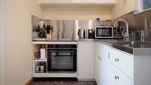 A compact kitchen with stainless steel appliances, white cabinetry, and a built-in oven.