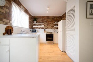 A compact kitchen with white cabinets, a microwave, an oven, and a refrigerator.