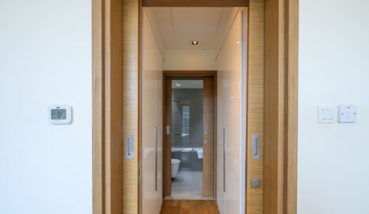 Un couloir étroit aux murs lambriss és, avec une porte donnant sur une salle de bain.