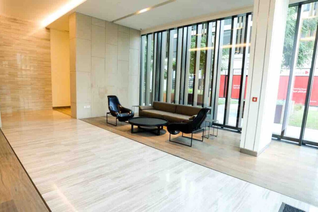 Un hall d’entrée spacieux au design moderne, comprenant un canapé et deux fauteuils, une table basse et de grandes fenêtres donnant sur l’extérieur.