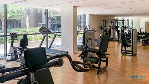 Un gimnasio con cintas de correr, máquinas de pesas y pesas libres.