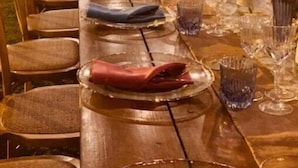 A long wooden table set for a formal outdoor event with chairs, glassware, and floral centerpieces. - Apartment in Farmhouse with Swimming Pool in the Tuscan countryside of Cortona (cortona)